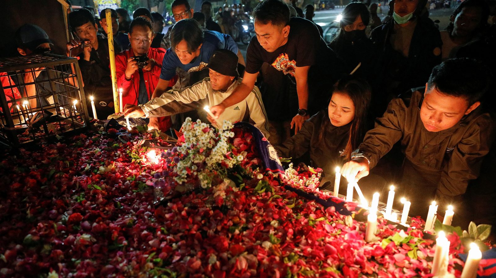 Människor lägger blommor vid minnesplatsen efter en supporterkatastrof i Indonesien